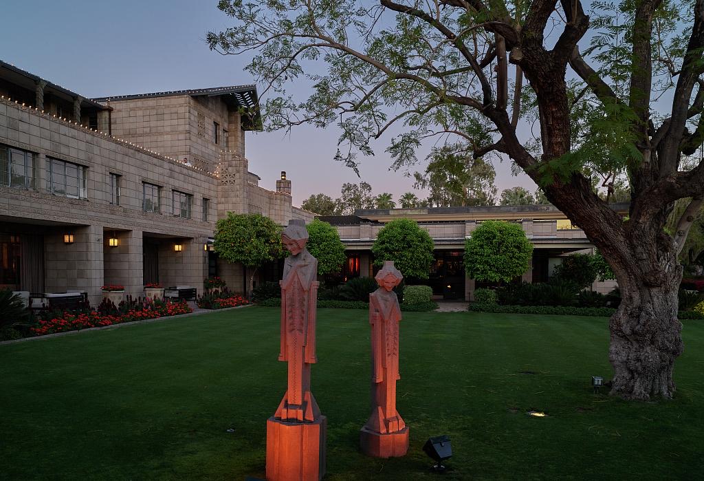 The Sprite statues uplit on the lawn of the Arizona Biltmore at dusk, its textile-block facade behind them